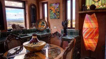 A dining area with a view, featuring a table with a bowl, chairs, and a stained glass window.