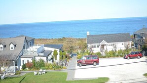 A coastal residential area with houses, a red van, and a clear view of the ocean. - The Inn at Spring House (Block Island)