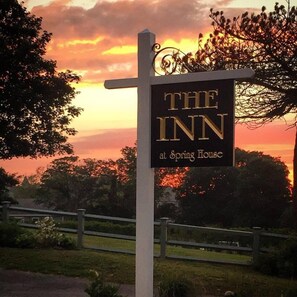 A sign for 'The Inn at Spring House' with a sunset background.