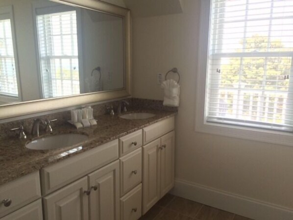 A bathroom with two sinks, a large mirror, and a window with blinds. - The Inn at Spring House (Block Island)