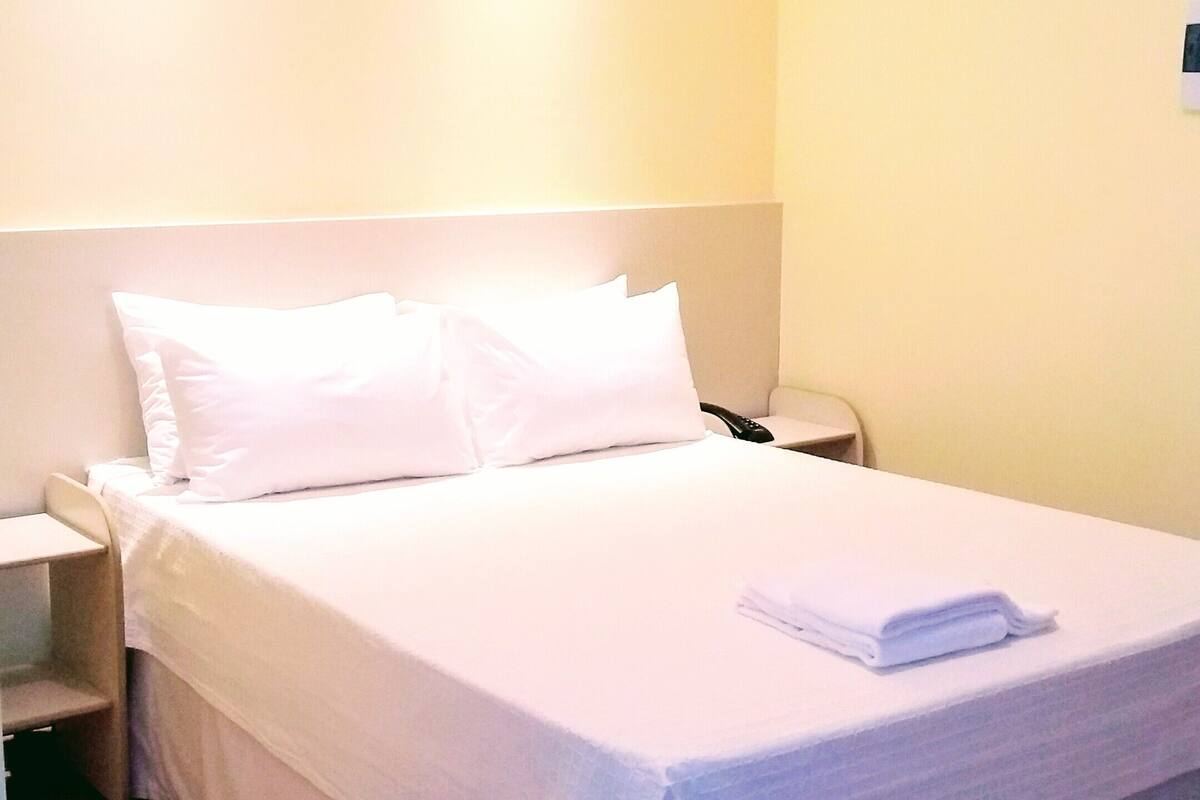 Una cama bien hecha con sábanas blancas en una habitación de hotel.