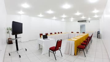 A conference room with a long table, chairs, a TV, and an air conditioning unit.