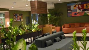 A modern lobby with a grey sofa, orange couch, and potted plants. - Belém Soft Hotel (Belém)