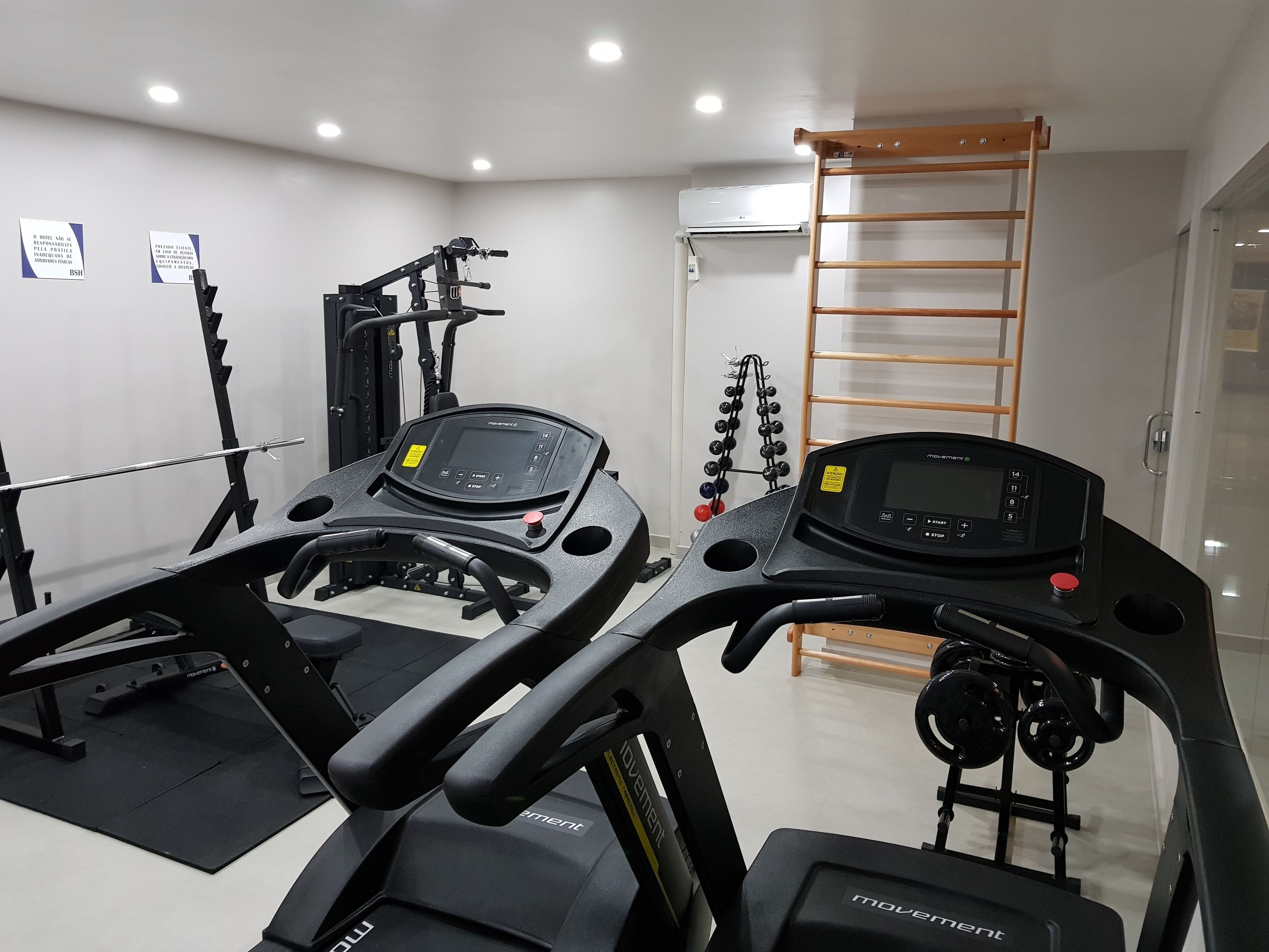 Un gimnasio con cintas de correr, máquinas de pesas y una barra para dominadas.