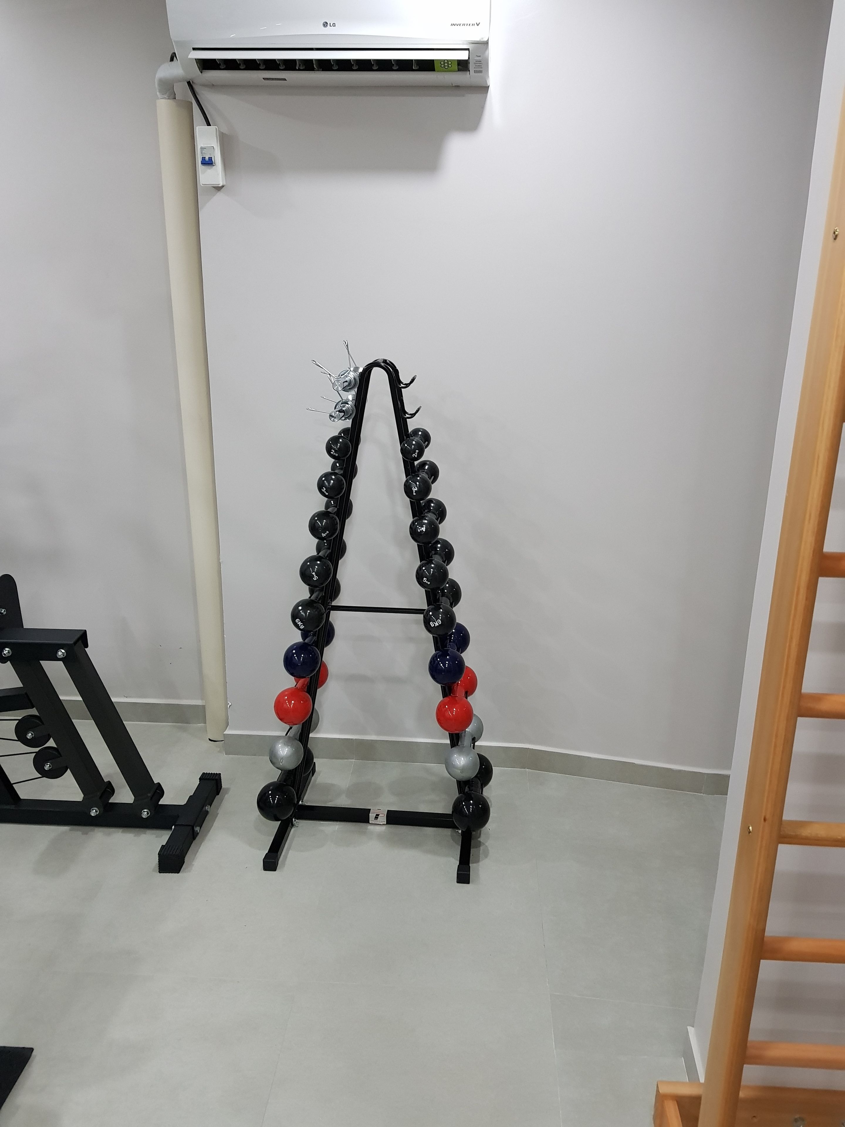 Ein Fitnessraum mit Hantelständer, Wand-Klimaanlage und Holzlader.