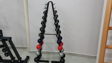 Una palestra con un portarattami, un condizionatore d'aria a parete e una scala in legno.