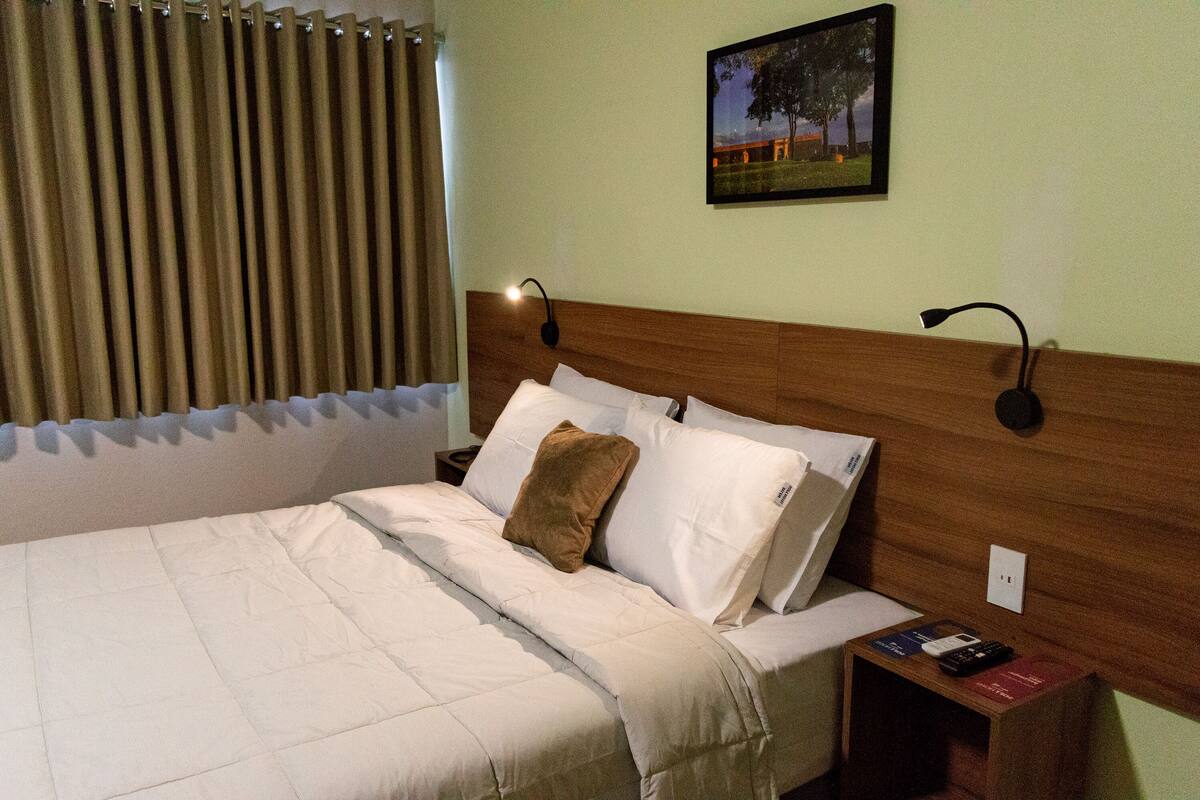 Ein Hotelzimmer mit einem großen Bett, einem Holzkopfende, zwei Nachttischen und einem Beistelltischchen mit einer Lampe.