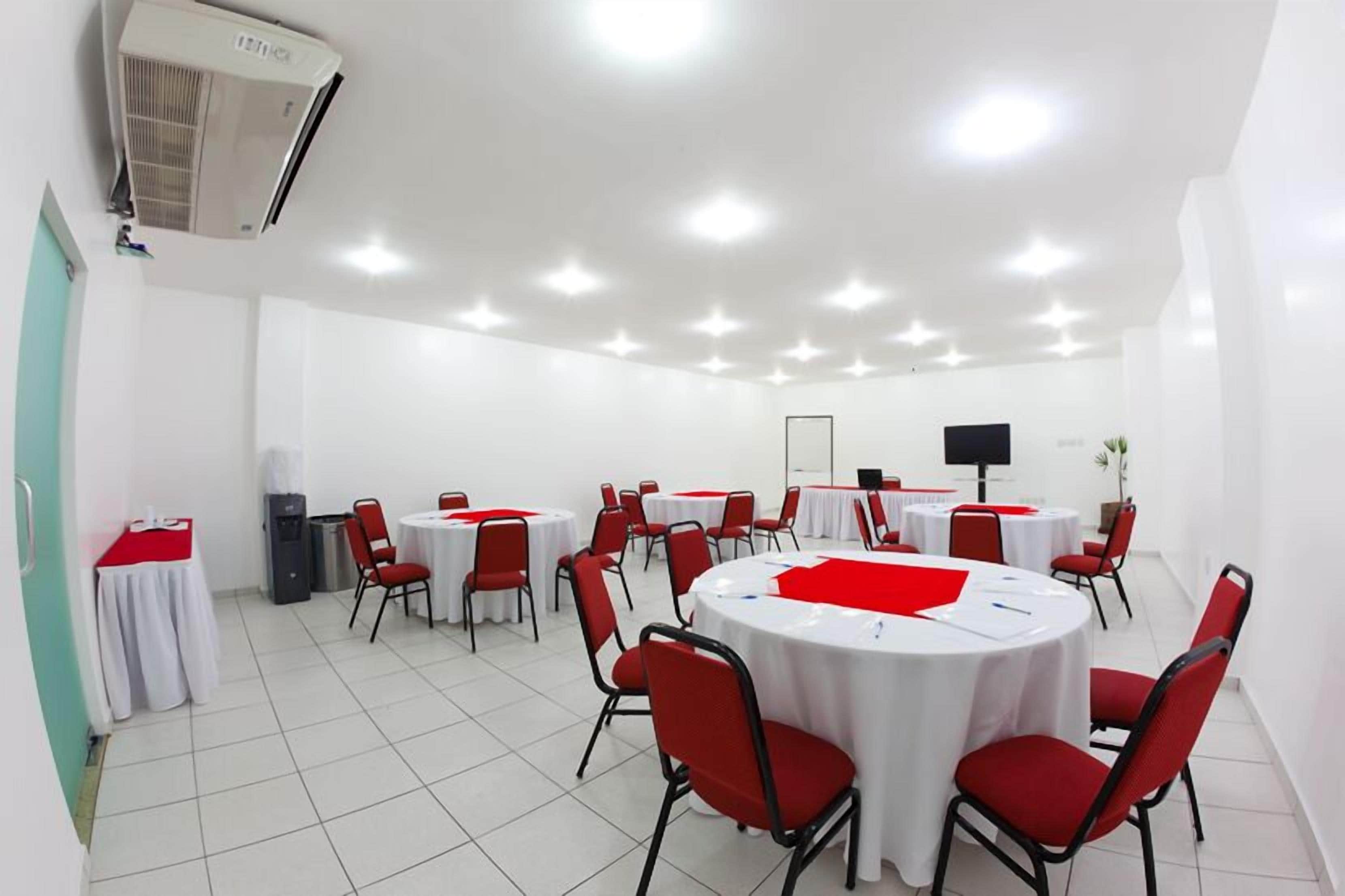 A conference room with round tables, red chairs, a projector, and a whiteboard.