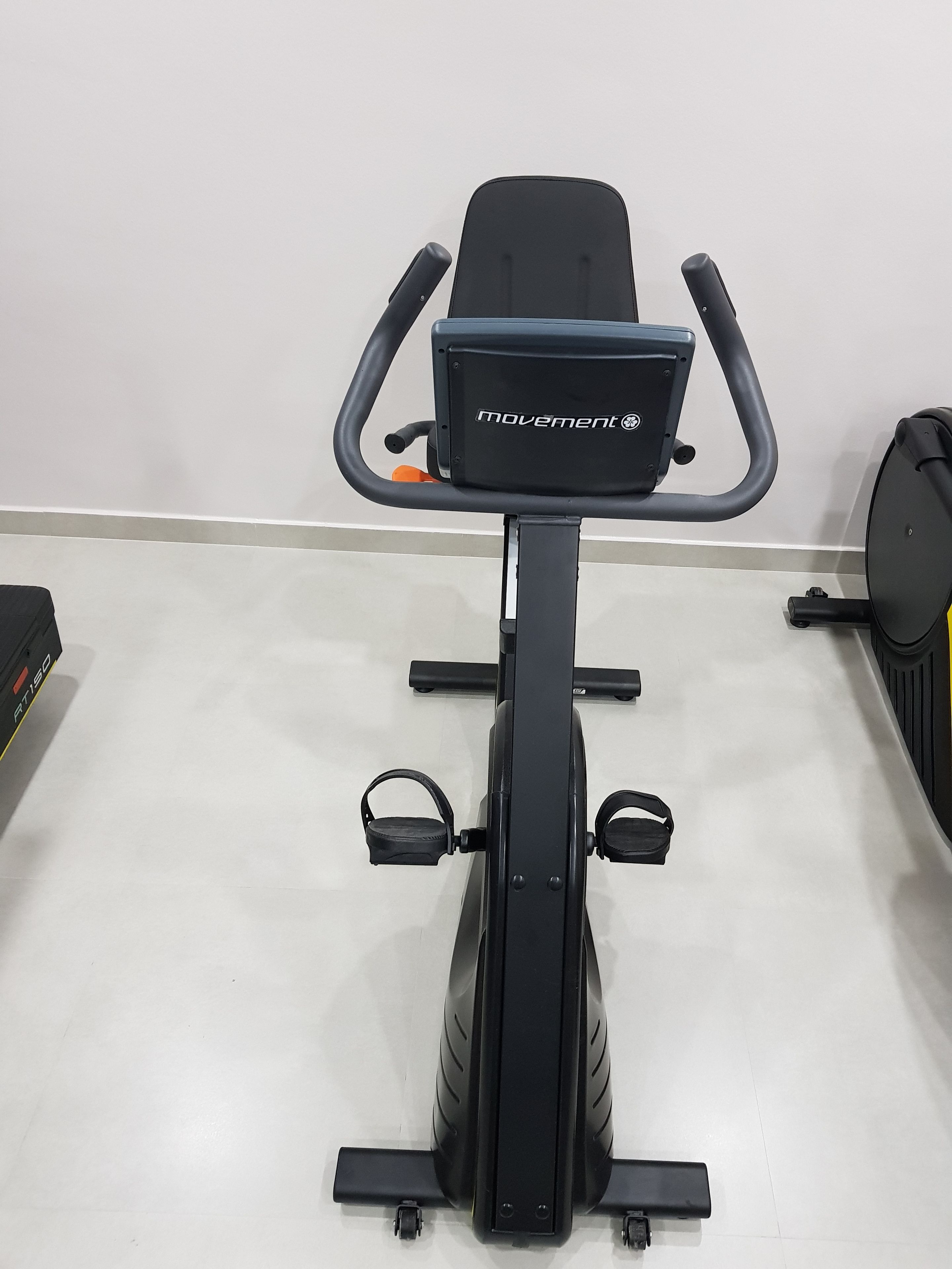 A stationary exercise bike with a control panel, handlebars, and footrests.