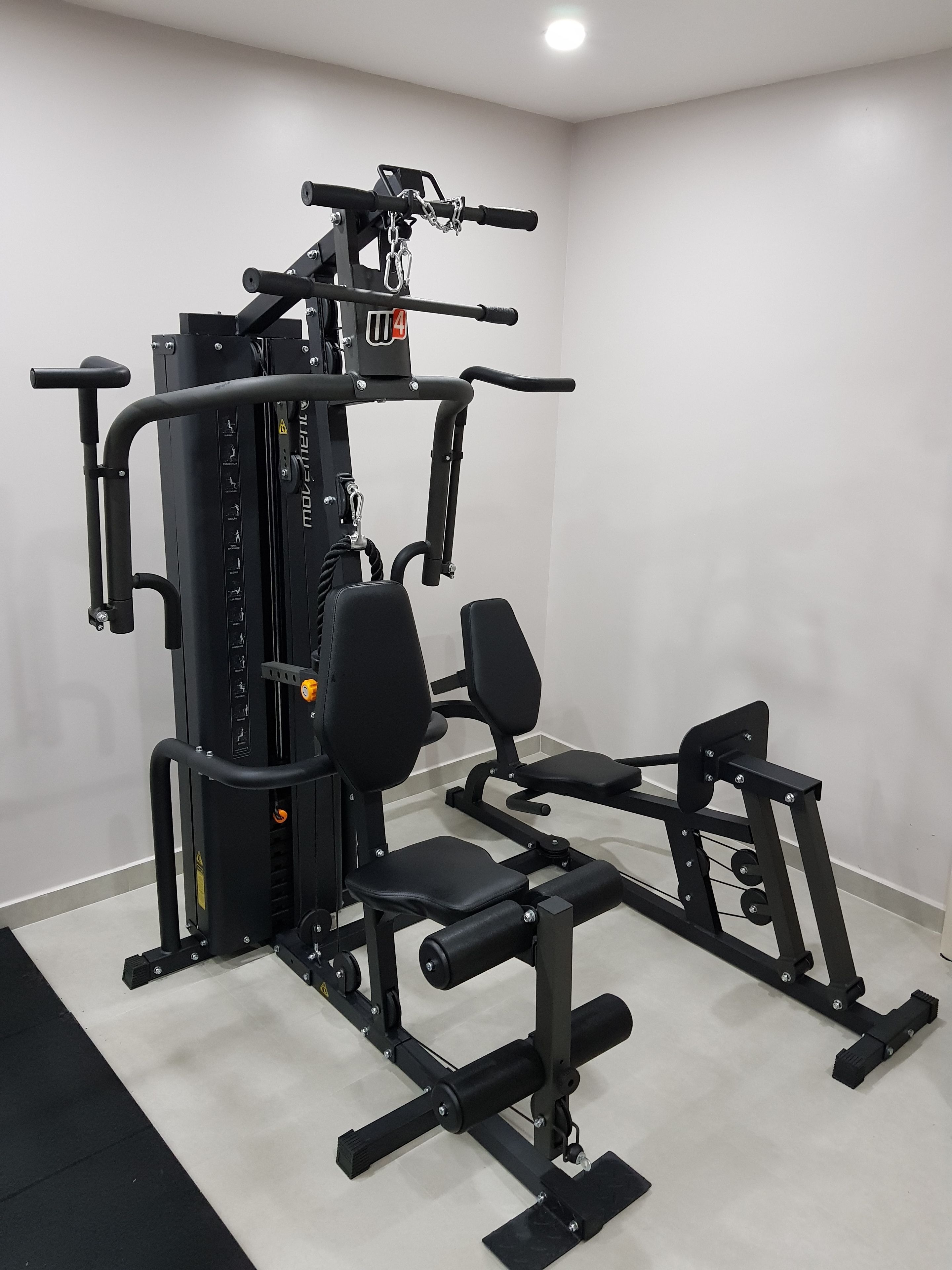 A compact home gym with a multi-functional workout station, including a squat rack, bench press, and various weight plates.