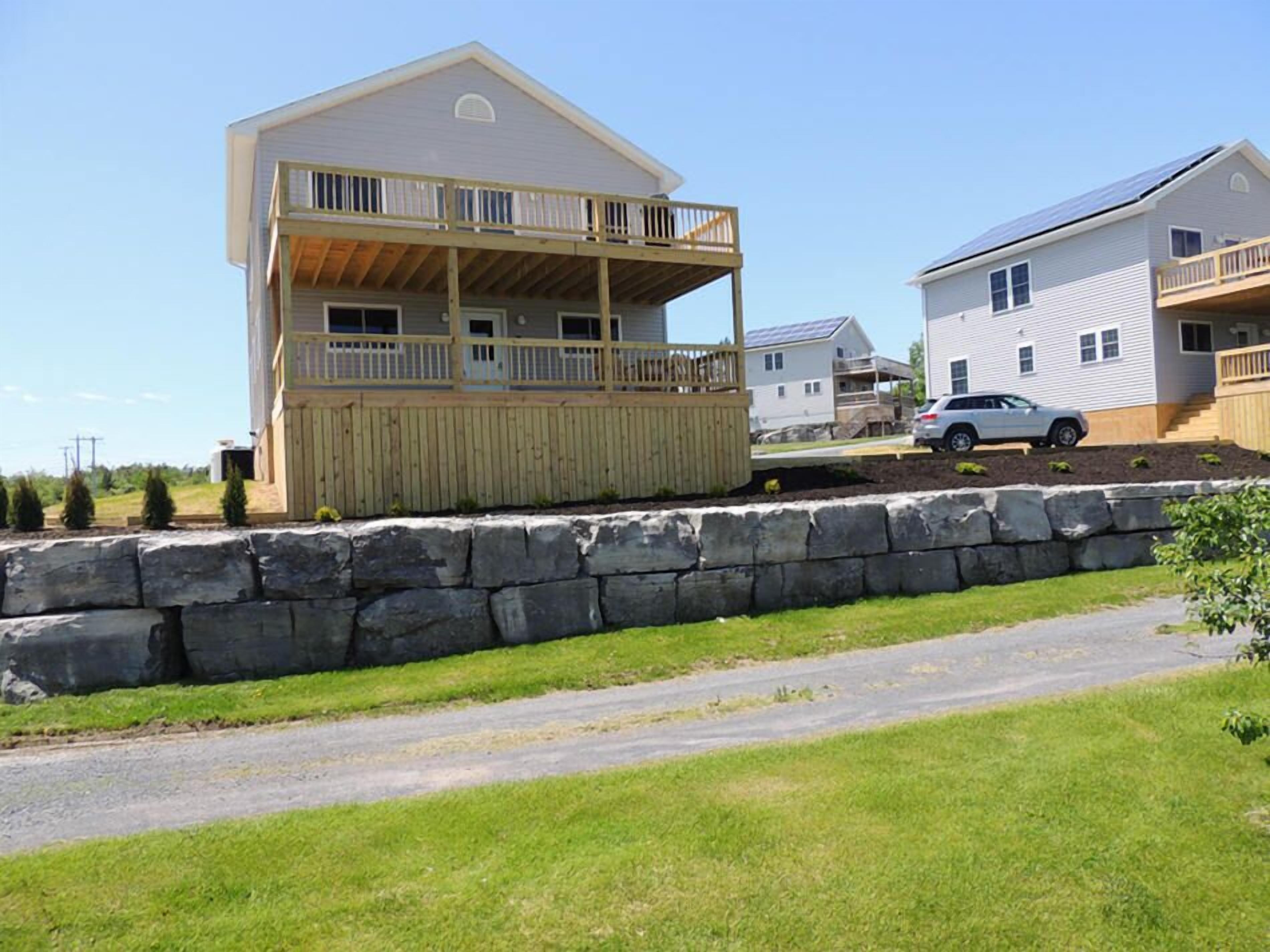 A two-story building with a balcony and a stone retaining wall in front.