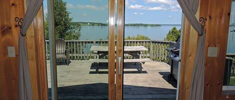 Une terrasse en bois avec une table de pique-nique et un barbecue, donnant sur un lac.
