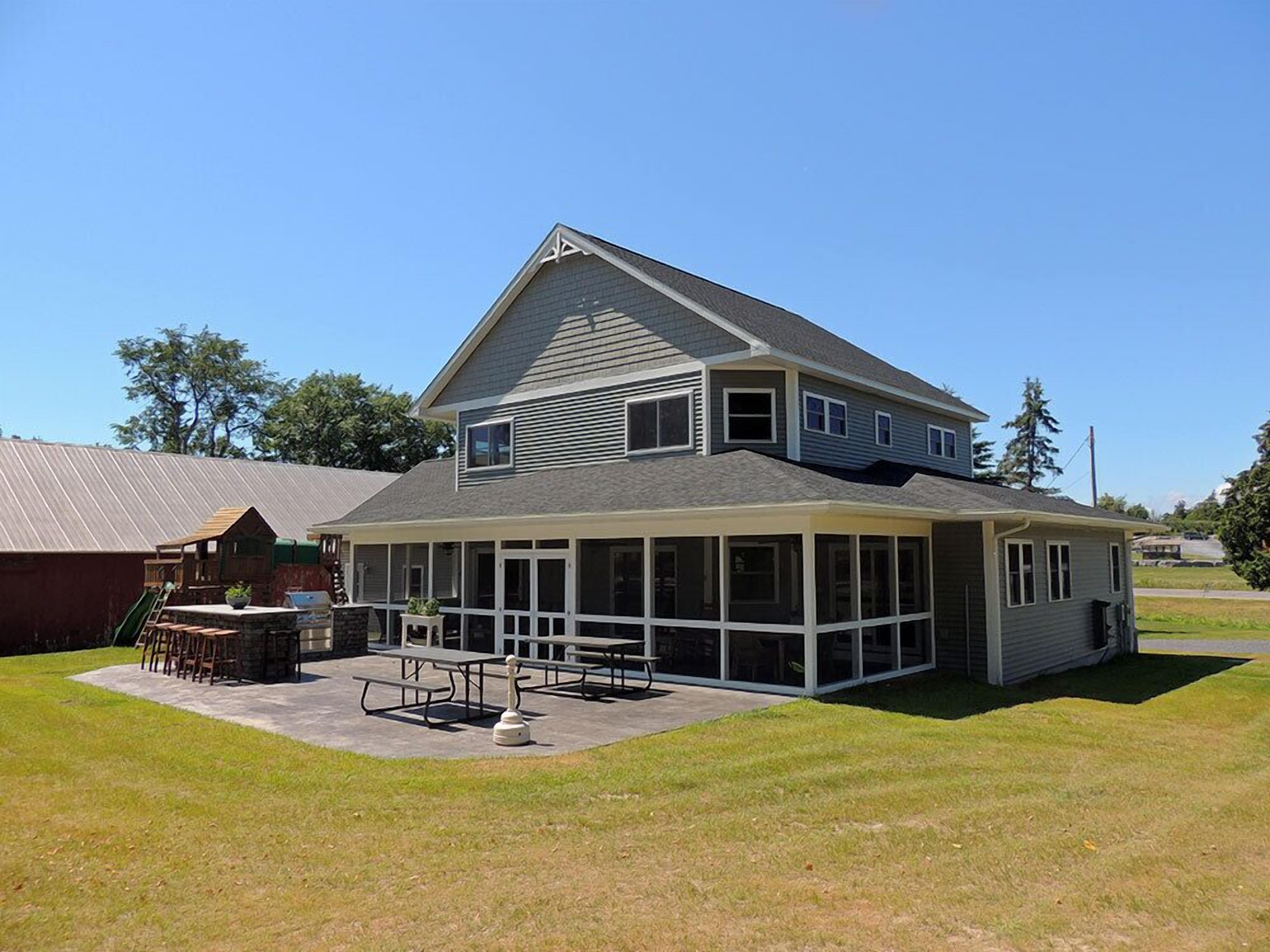 A two-story house with a covered patio area, a small shed, and a lawn.