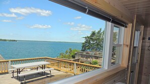 Une terrasse en bois avec une table et des chaises donnant sur une étendue d’eau.