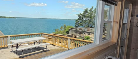A wooden deck with a table and chairs overlooking a body of water.