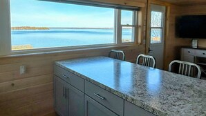Une cuisine aux murs en bois, dotée d’un plan de travail en granit et offrant une vue sur la mer.