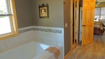 A bathroom with a large bathtub, wooden doors, and a tiled floor.