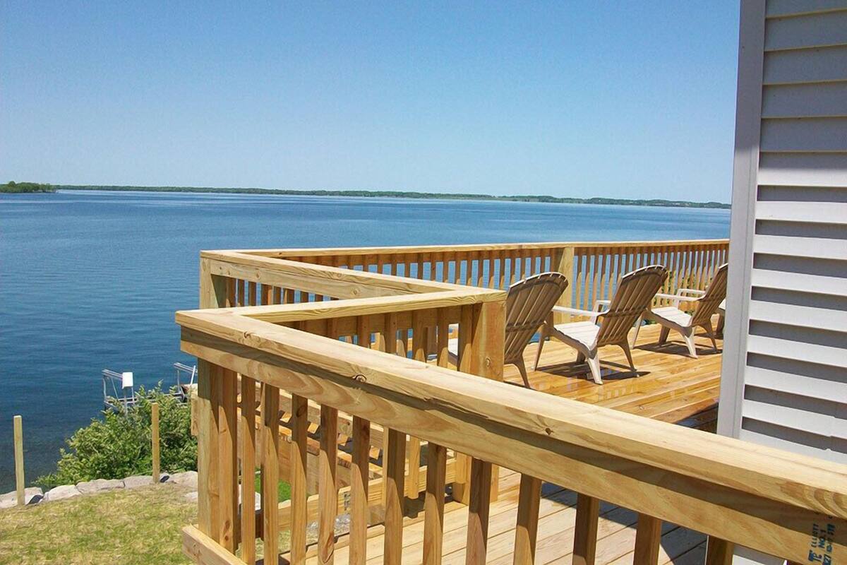 Terraza de madera con sillas que da a un lago.
