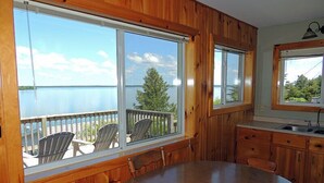 Un intérieur en bois avec de grandes fenêtres donnant sur un lac, une table ronde et des chaises.