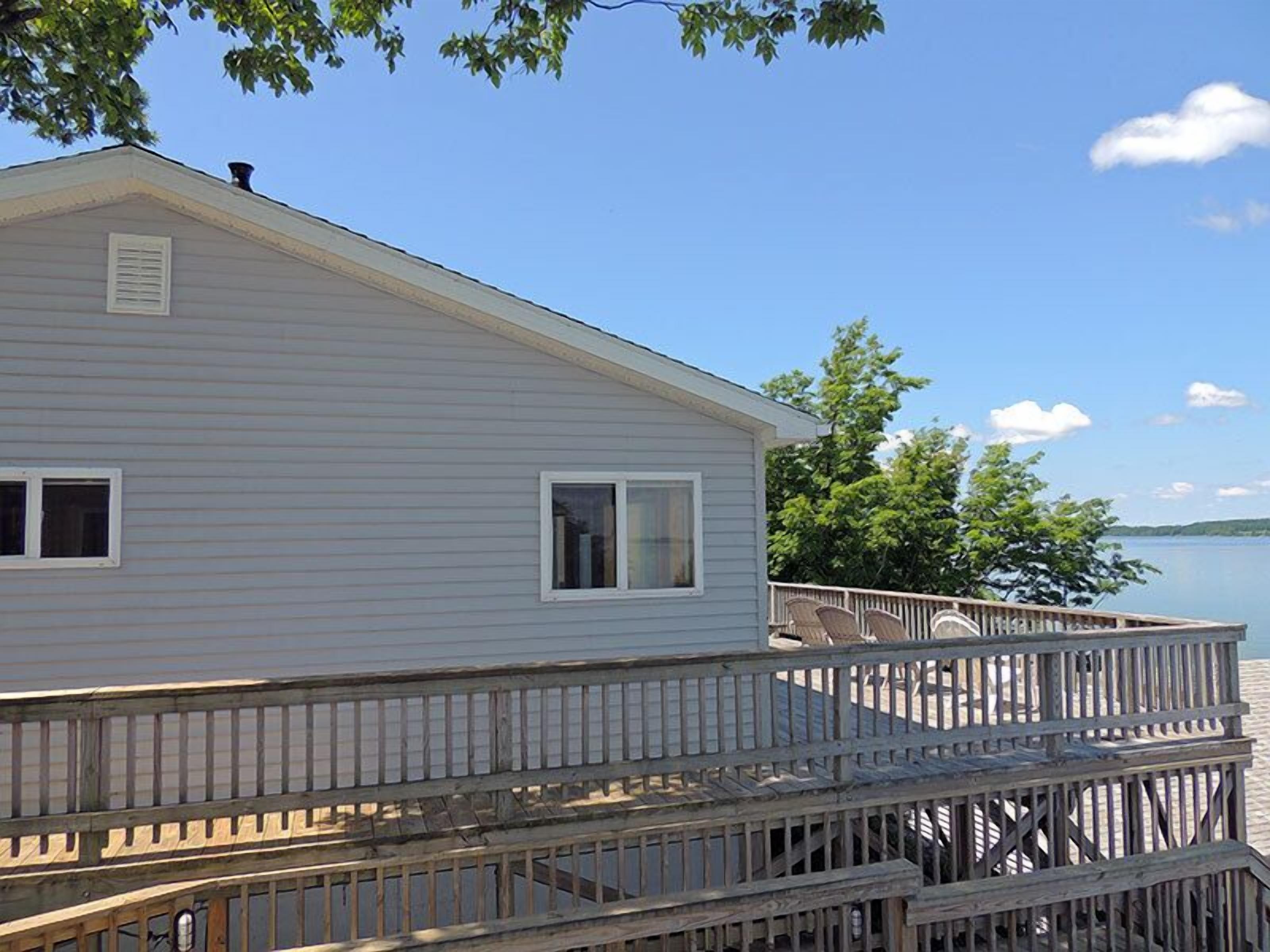 A single-story house with a wooden deck extending over a body of water.