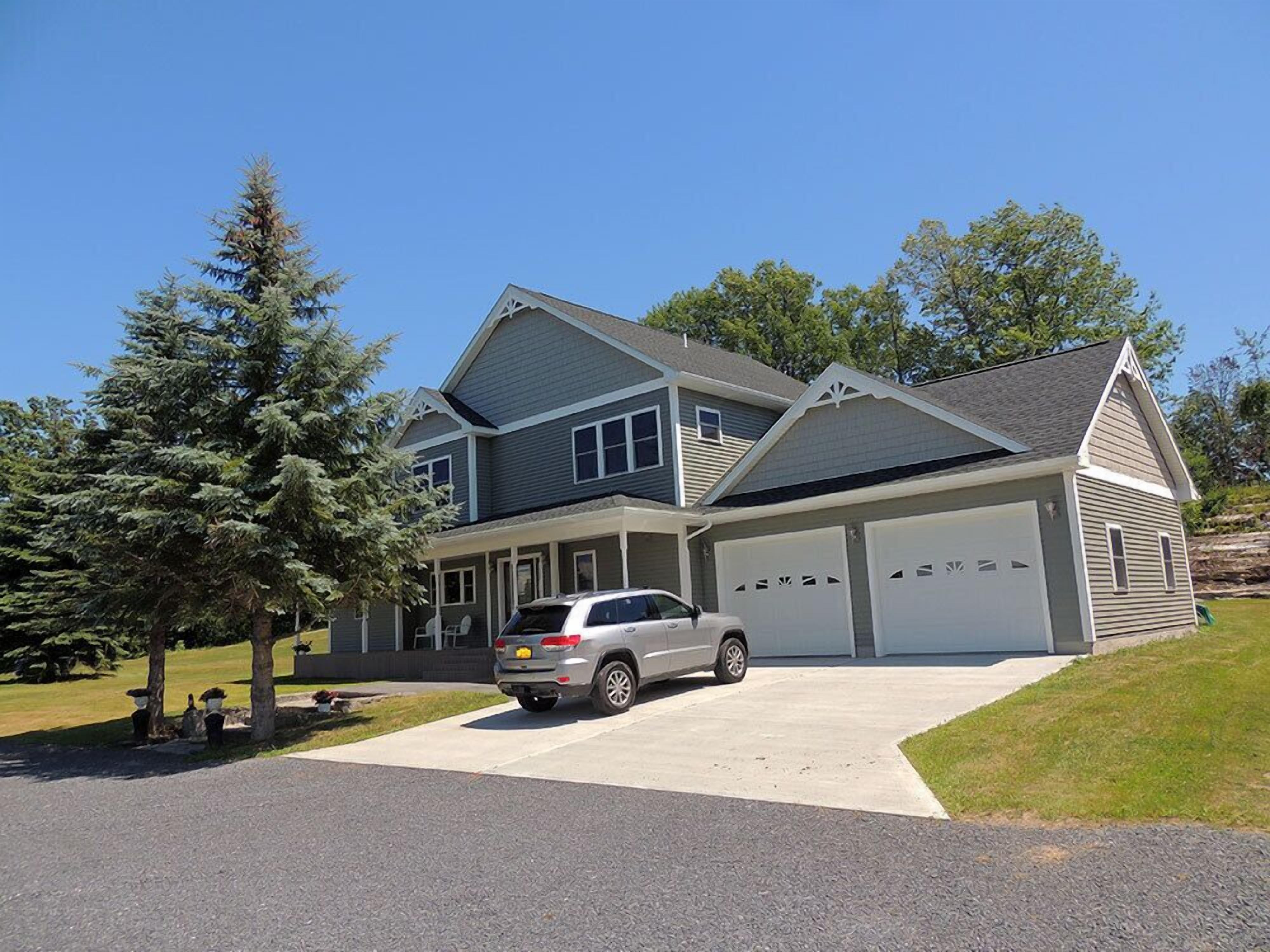 A two-story house with a garage, driveway, and a silver SUV parked in front.