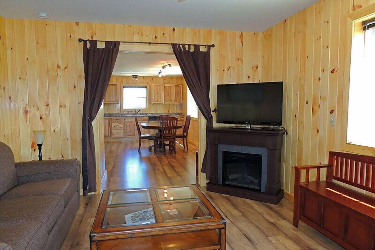 Una sala de estar acogedora con sofá, una mesa de centro de cristal, chimenea y televisor.