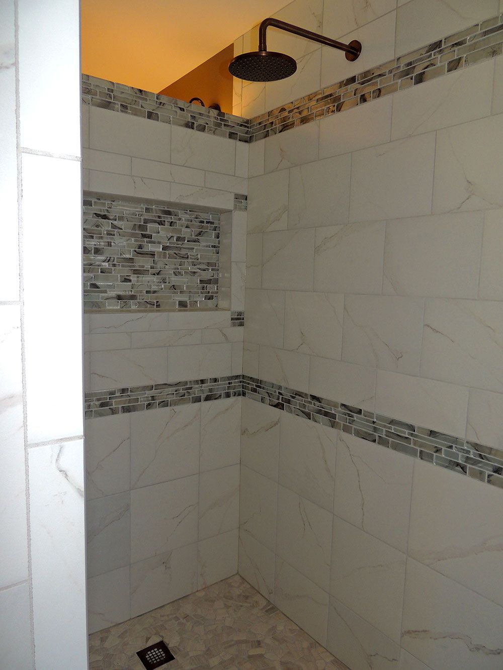 A shower with a rain showerhead, tiled walls, and a floor drain.