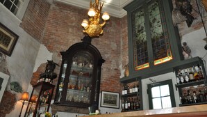 Een bar met een bakstenen muur, een kroonluchter en flessenkasten.