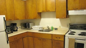 A kitchen with wooden cabinets, a microwave, a toaster, a sink, and a stove. - Yellowknife Polar Suite (Yellowknife)