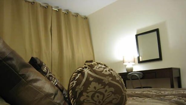 A hotel room with a bed, a nightstand, a lamp, and a mirror on the wall. - Yellowknife Polar Suite (Yellowknife)