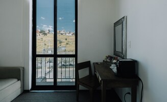 Una habitación con un ventanal grande, un escritorio, una silla y una cama.