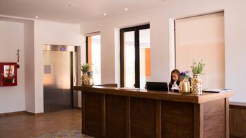A reception desk with a wooden finish, a fire alarm, and a large window.