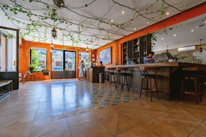 A spacious kitchen with a bar area, tiled flooring, and hanging plants. - Hotel La Estacion (San Miguel de Allende)