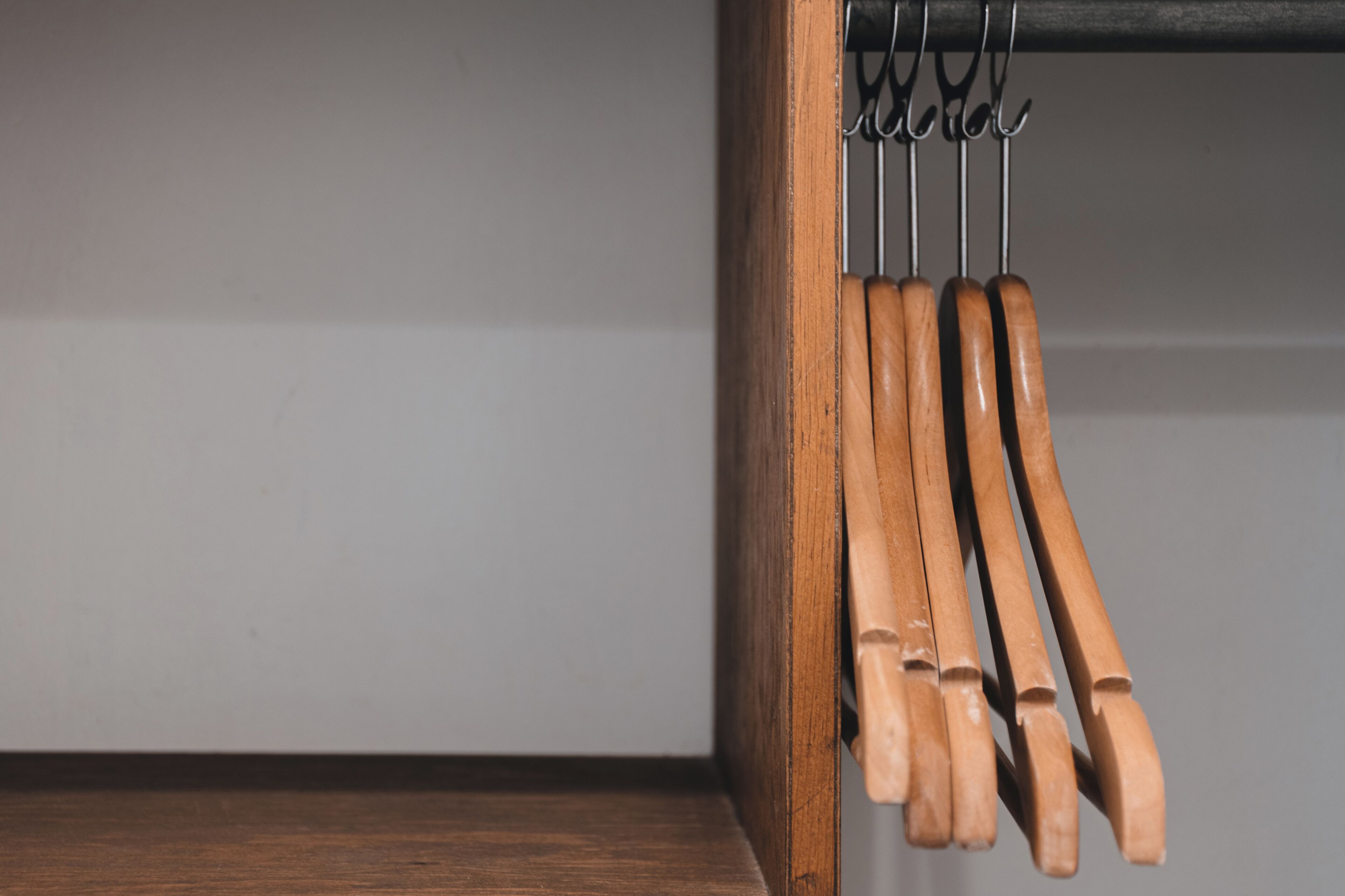 Uma prateleira de madeira com diversos utensílios de cozinha pendurados em um suporte de metal.