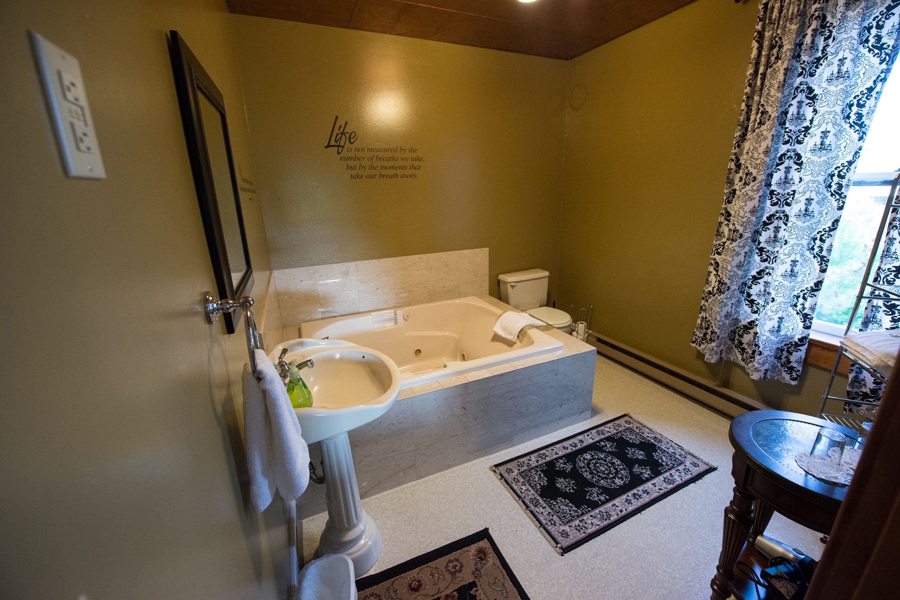 A bathroom with a bathtub, toilet, sink, and a mirror.
