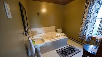 A bathroom with a bathtub, toilet, sink, and a mirror.