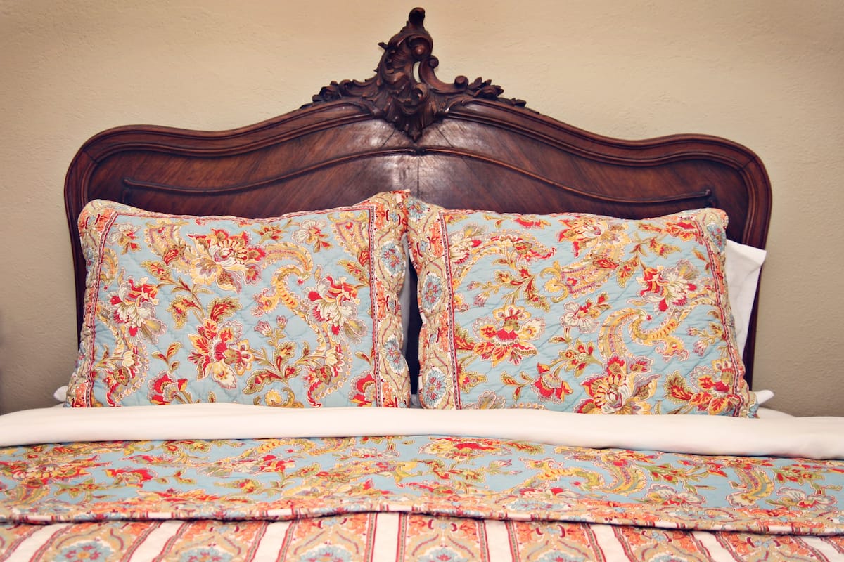 Una cama con una colcha de estampado floral y dos almohadas a juego.