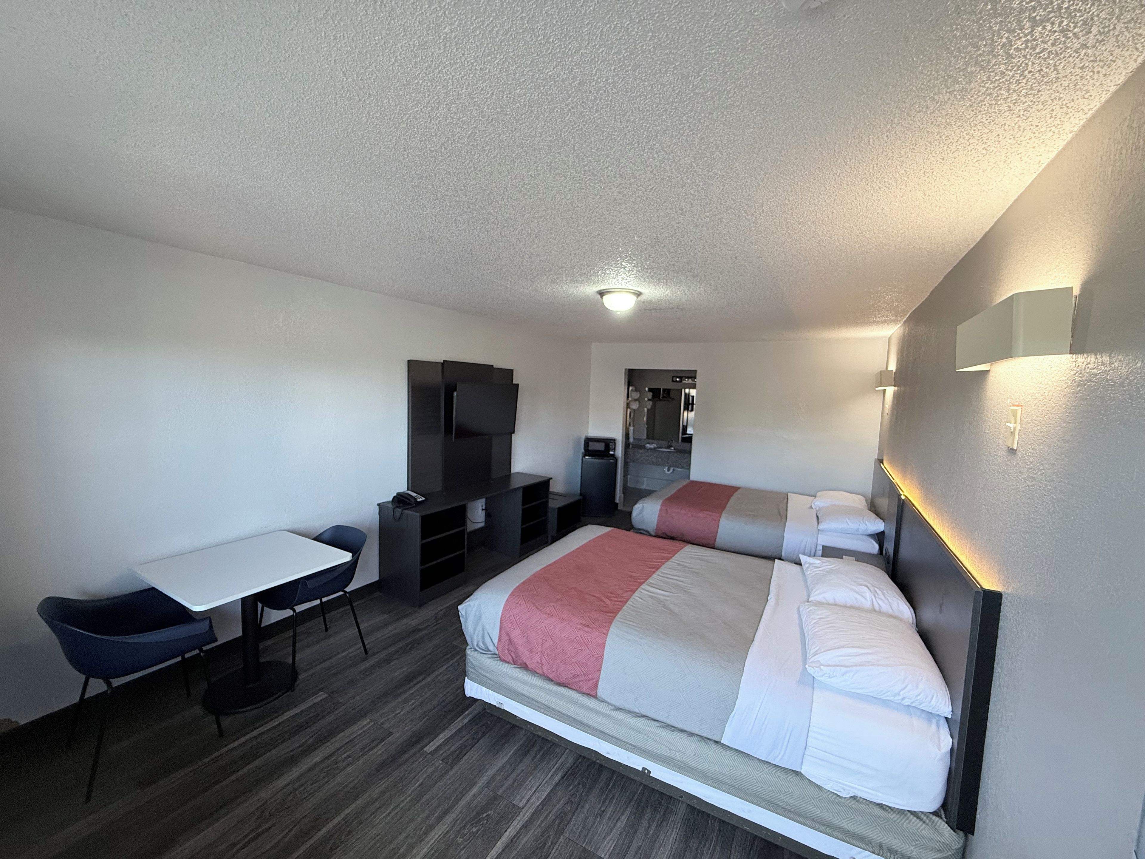 A hotel room with a bed, a desk, a chair, a television, and a mirror.