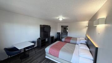 A hotel room with a bed, a desk, a chair, a television, and a mirror.