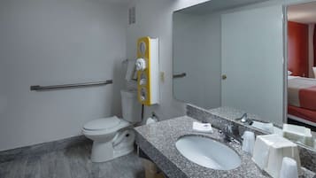 A modern bathroom with a toilet, sink, mirror, and towel dispenser.
