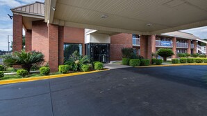 A hotel with a covered entrance, brick exterior, and a parking lot. - Motel 6 Montgomery, AL - Coliseum (Montgomery)
