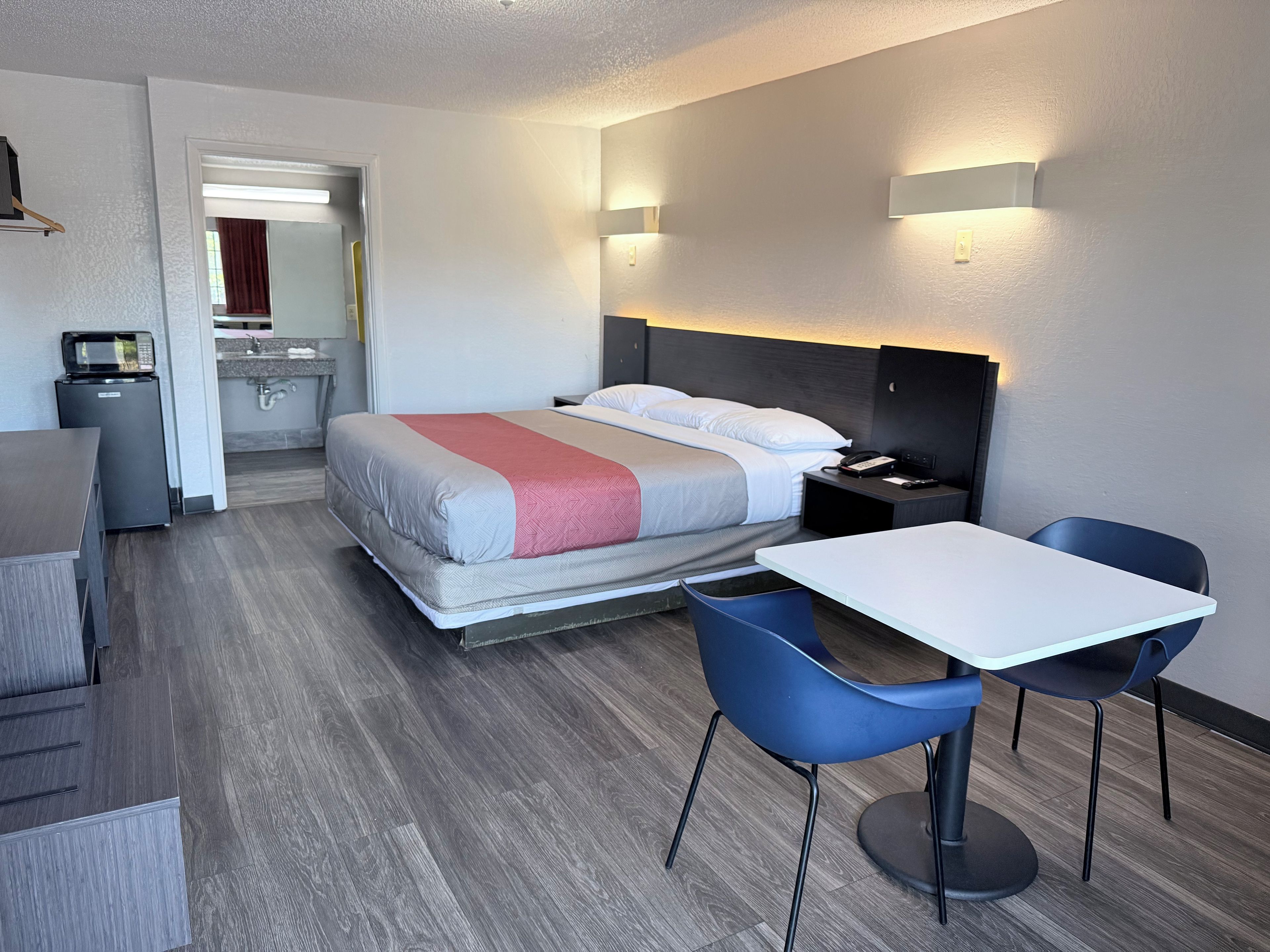 Ein Hotelzimmer mit Bett, Nachttisch, Sessel, Schreibtisch und einer Küchenzeile.