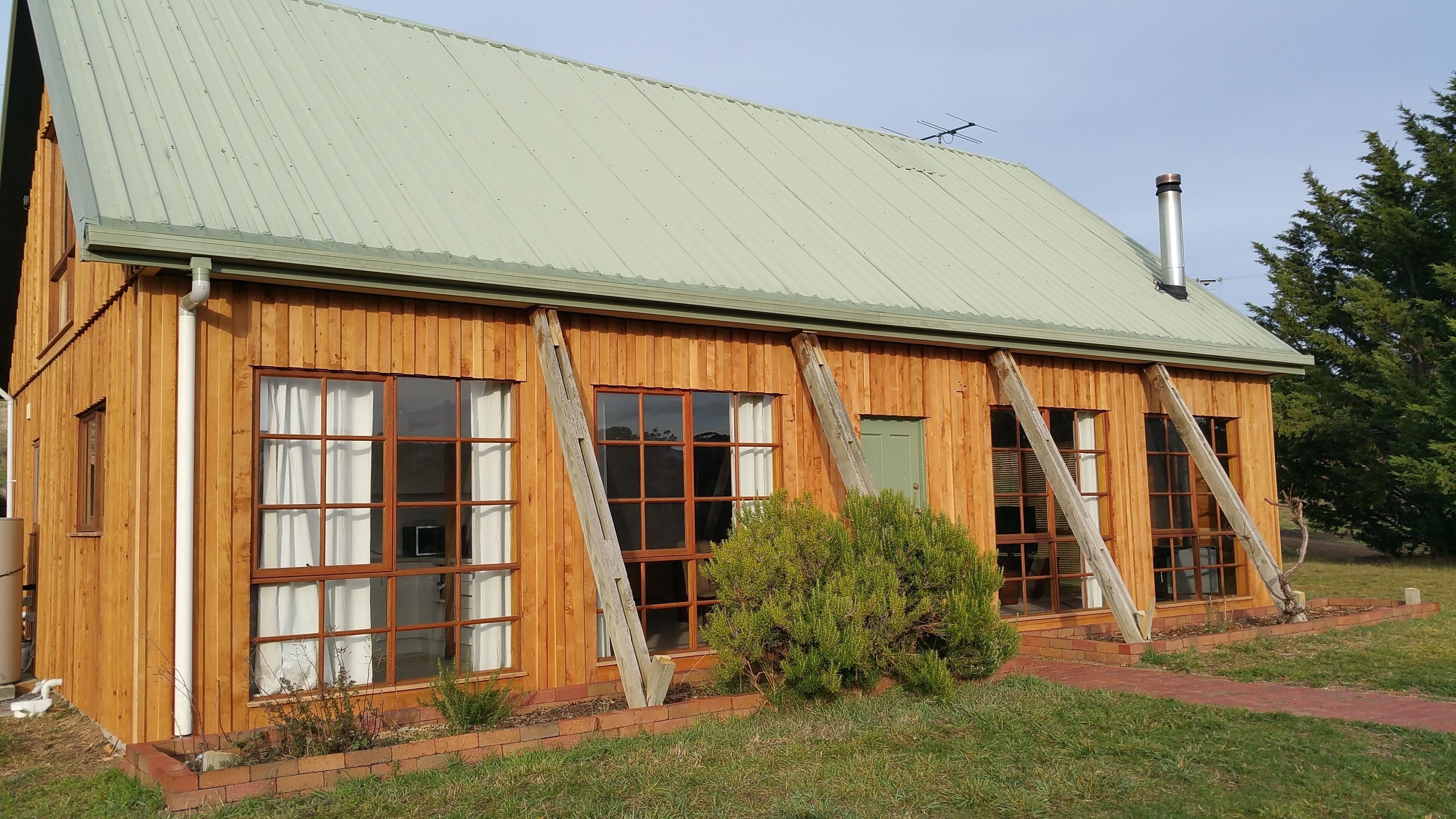 A wooden cabin with large windows and a metal roof.