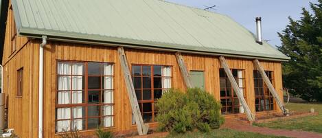 A wooden cabin with large windows and a metal roof.