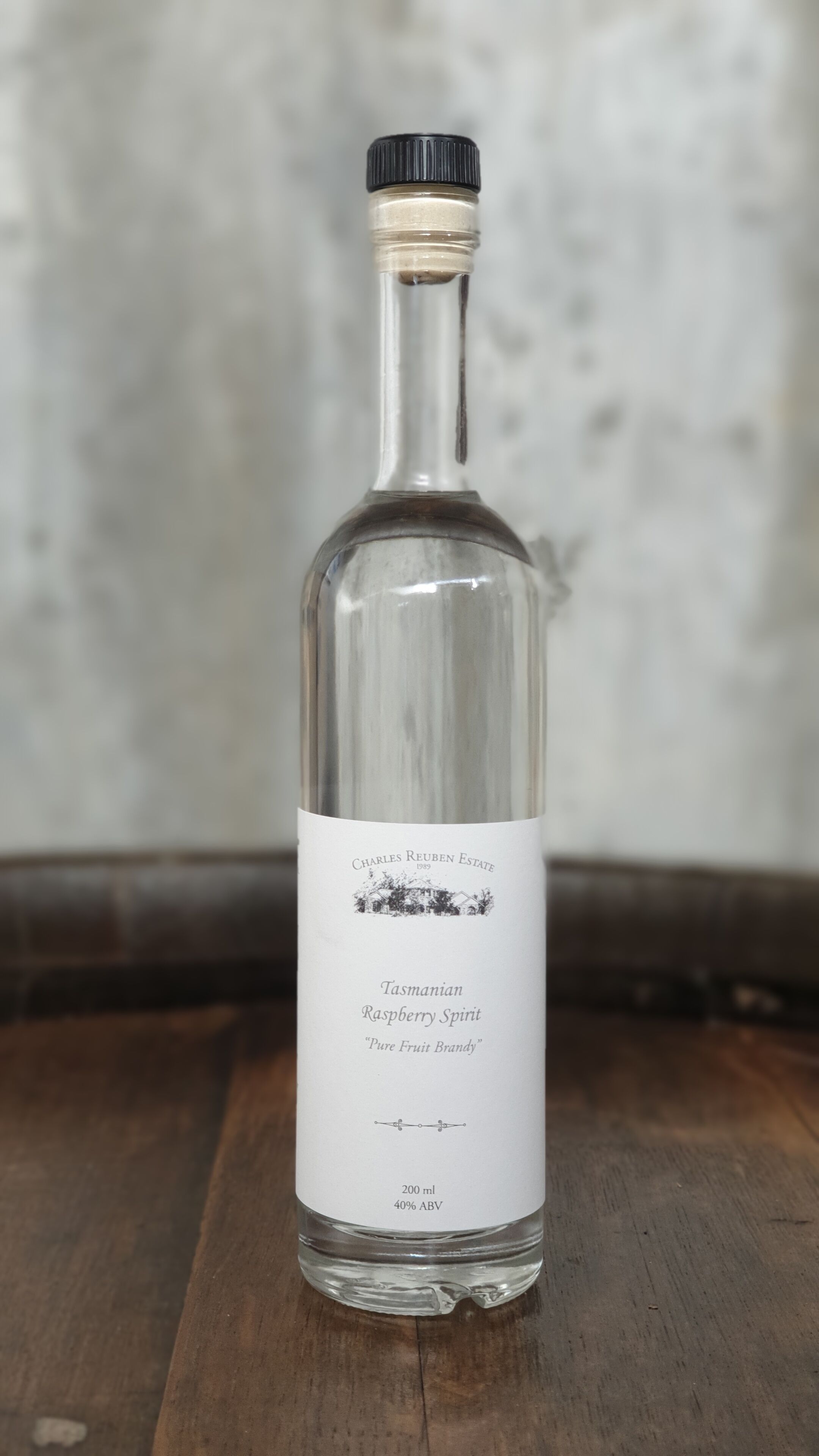 A bottle of Charles Reuben Estate Tasmanian Raspberry Spirit on a wooden surface.
