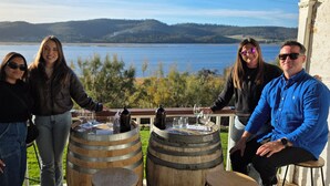 A group of people on a balcony with a scenic view of a lake and hills. - Charles Reuben Estate (Tea Tree)