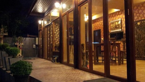 A building with large glass doors and windows, a brick pathway, and a stone wall. - Teeraya Boutique Guesthouse - Hostel (Chiang Mai)