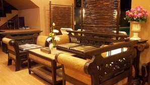 A traditional wooden sofa set with cushioned seating and a low table, accompanied by a decorative vase with flowers. - Teeraya Boutique Guesthouse - Hostel (Chiang Mai)