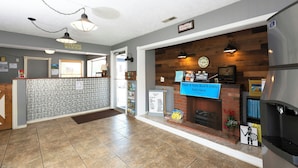 A reception area with a fireplace, a sign for Noah & Sons Board Game, and a 'Home' sign on the wall. - Sunrise Inn Williamstown (Williamstown)