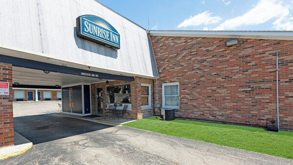 Pousada Sunrise com entrada desimpedida, fachada de tijolos e área de estacionamento.